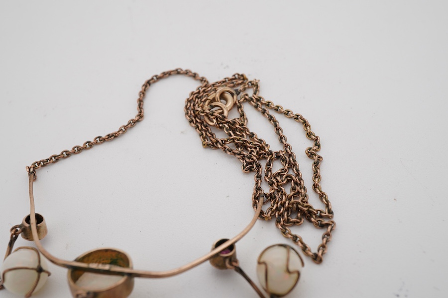 An early 20th century yellow metal, thee stone white opal and three stone garnet set drop necklace, approximately 44cm.